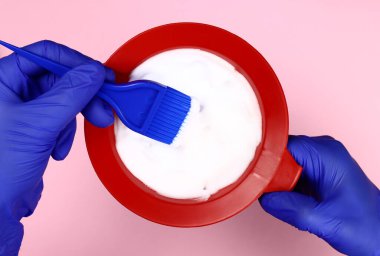 Kuaför plastik kasede saç boyasını karıştırır.