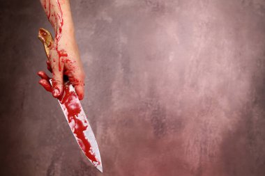 Gri arka planda kanlı bir bıçak tutan kanlı kadının eli. Şiddet, cinayet kavramı