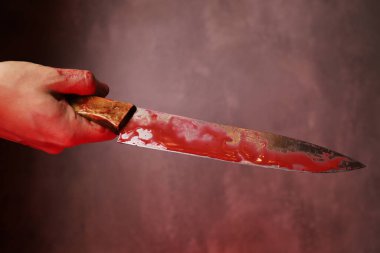 Gri arka planda kanlı bir bıçak tutan kanlı kadının eli. Şiddet, cinayet kavramı