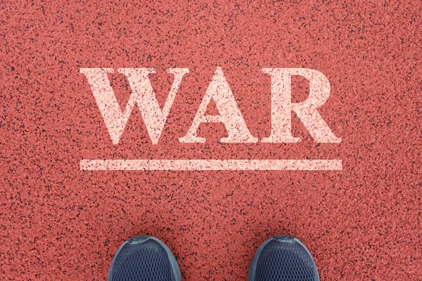 Feet stand in front of the word War