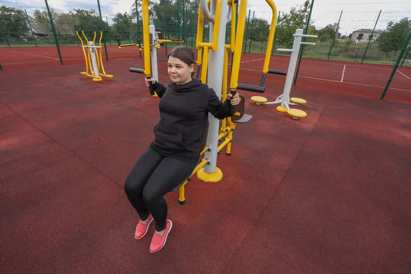 Woman doing exercises on a street sports ground