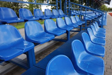 Stadyum tribününde mavi plastik koltuklar.