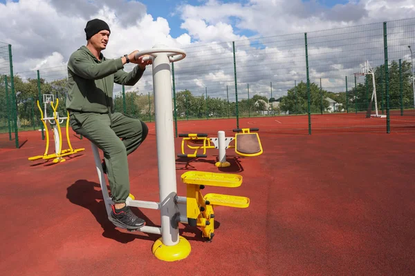 Man on exercise bike at city outdoor sports ground