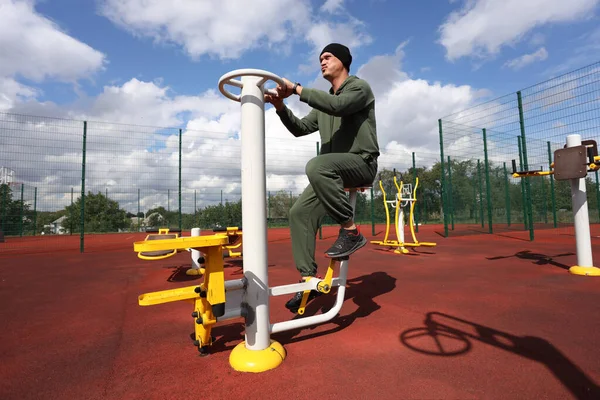 Man on exercise bike at city outdoor sports ground