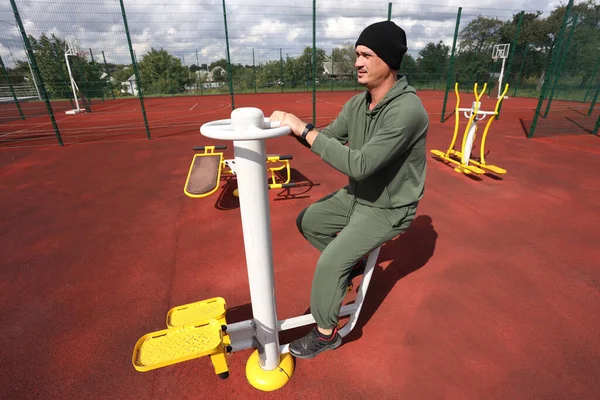 Man on exercise bike at city outdoor sports ground