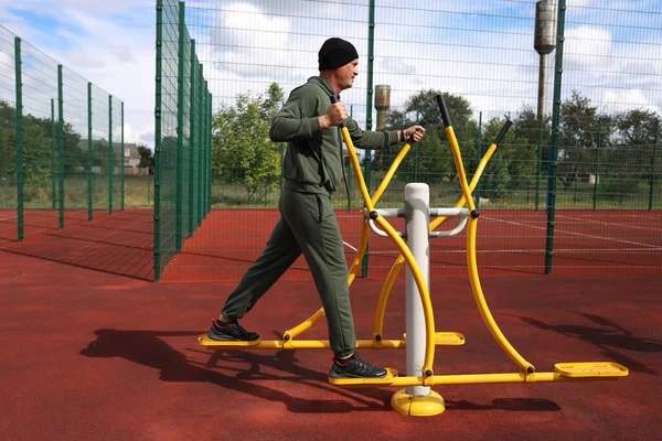 man trains on a trainer on a sports ground.