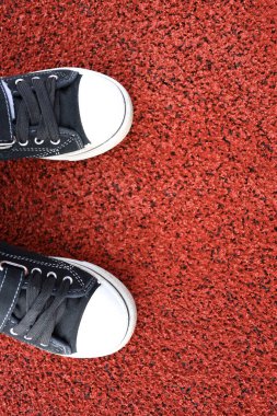 Lastik koşu pistinde çocuk ayakları spor ayakkabılarındaydı. Dikey Yönlendirme