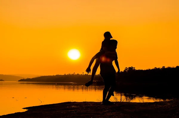 Silueta pareja en la orilla del lago — Foto de Stock