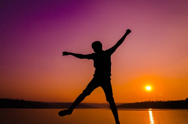 Silueta hombre saltando en la orilla del lago — Foto de Stock