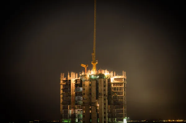Краны строят большие здания ночью — стоковое фото