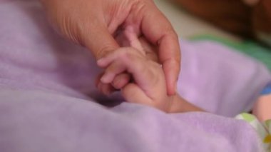 Yeni doğmuş bir bebeğin eliyle oynayan kadının eli, seçtiğiniz alan derinliğinin derinliği