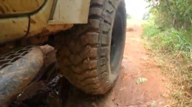 4x4 off road pikap tekerlekleri toprak bir yolda çalışıyor. Kirli yolda çamurlu, ıslak ve kuru çamurla hareket eden off-road kamyon tekerlekleri. Bakış açısına göre 4WD kamyon lastiği taşrada seyahat ediyor.