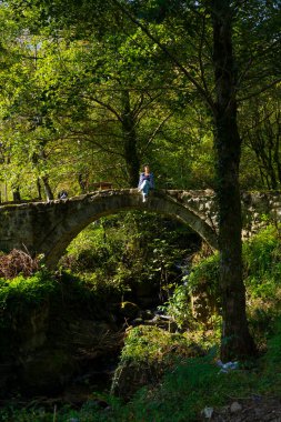 Machakhela, Gürcistan - 16 Ekim 2021: Nehrin üzerindeki köprüde oturan kız