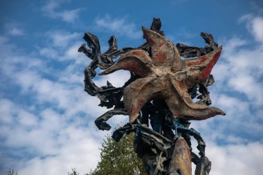 Terk edilmiş bir binanın çatısında mavi gökyüzüne karşı duran eski püskü bir yıldız. Eski Sovyet mimarisinin kalıntıları..