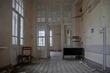 Terk edilmiş bir hastanede kapıları olan güzel bir koridor. Pencerenin dışındaki sokakta. Eski püskü duvarlar. Terk edilmiş bir binanın içi. Tahta kapılar..