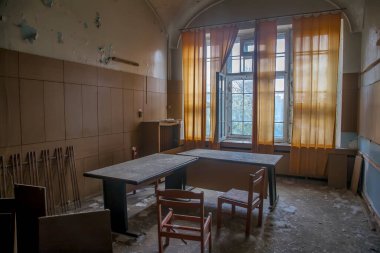 Terk edilmiş bir hastanede eski bir oda. Büyük pencere. Pencereden ışık geçiyor. Eski püskü duvarlar. Terk edilmiş bir binanın içi..