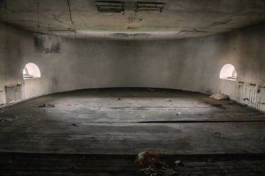 Terk edilmiş bir malikanede boş, ürkütücü, yuvarlak bir oda. Işık ışınları iki pencereden geçer. Kalitesiz taş duvarlar. Terk edilmiş eski bir ev..