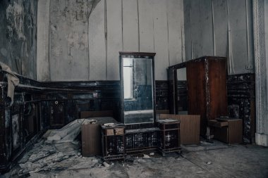 Terk edilmiş bir evde mobilyaları olan antika bir oda. Eski ayna. Aynadaki ışığın yansıması. Küflü eski püskü duvarlar. Tahta mobilyalar. Terk edilmiş bir malikanede bir oda.
