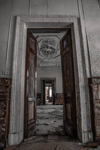 A beautiful high doorway in an old abandoned manor house. Old wooden doors. Shabby walls with mold Ancient architecture.