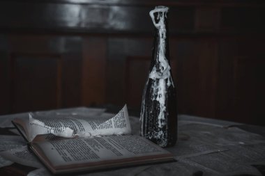 An empty bottle of wax and an old book lie in the room of an abandoned house. Scary interior. Old abandoned items. The wax runs down the bottle.