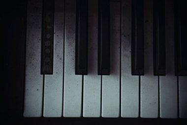Terk edilmiş bir piyanonun siyah beyaz anahtarları. Eski bir müzik aleti. Işık ve gölge oyunu. Unutulmuş piyano.