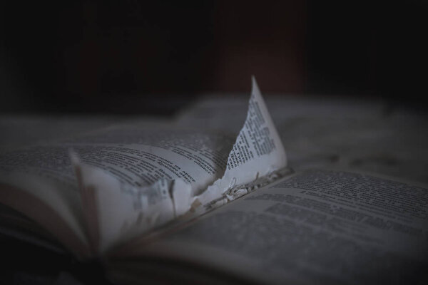 An old book with a torn page lies in an abandoned building. Gloomy atmosphere. An old book. Abandoned building.