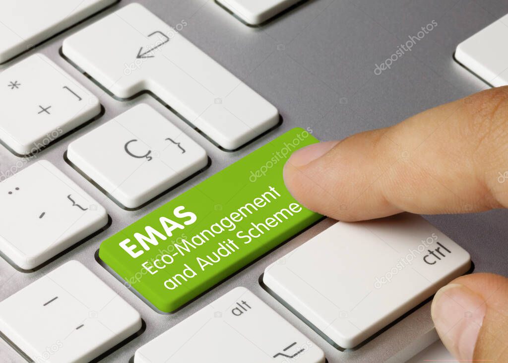 EMAS Eco-Management and Audit Scheme Written on Green Key of Metallic Keyboard. Finger pressing key.