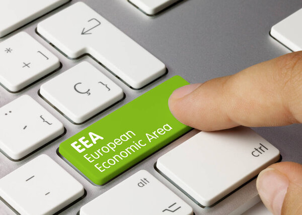 EEA European Economic Area Written on Green Key of Metallic Keyboard. Finger pressing key.
