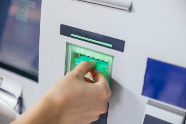 Woman inserting a credit card in ATM bank machine to transfer money or withdraw. Finance customer and banking service concept
