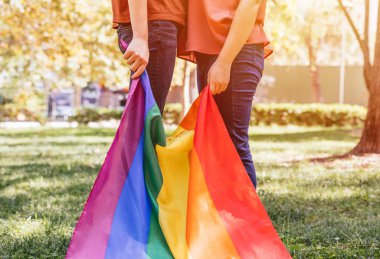Lezbiyen bir kadın çift, LGBTQ gökkuşağı bayrağı taşıyor. Homoseksüel topluluğun sembolü. Gurur ayı için gey bayrağı ve cinsel ve aşk çeşitliliğinin kutlandığı gün