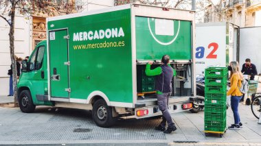 Valencia, İspanya - Mayıs 2021. Mercadona teslimat kamyonu yolda, teslimatçı da çalışıyor. Mercadona en popüler ve en büyük İspanyol süpermarket zincirlerinden biridir.