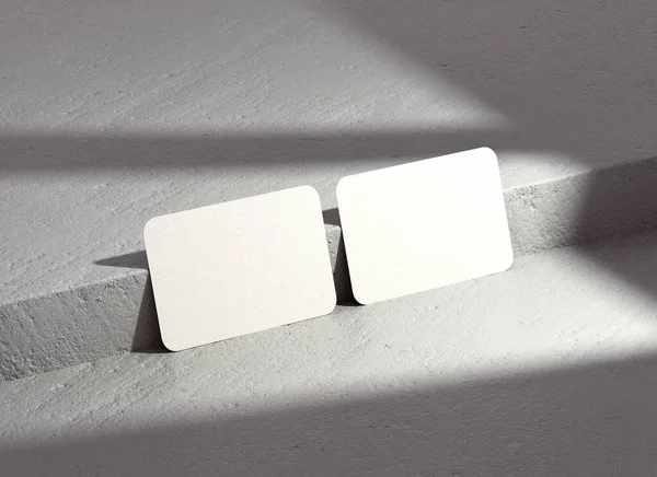 Two rounded corners business card mockup with shadows for branding presentation, corporate identity, stationery template on a concrete background. Modern paper mock up in realistic 3D rendering