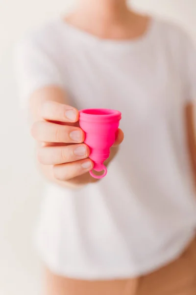 Close up of a woman hand holding a pink menstrual cup. Zero waste, eco and reusable alternatives for period and female hygiene concept
