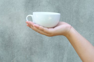 Arka planda bir fincan kahveyi tutan el..