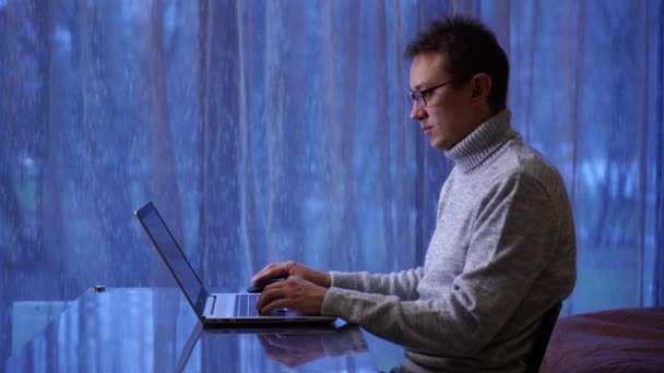 Hombre freelancer concentrado en anteojos trabajando remotamente en casa Videoclip