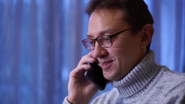 Junger Mann in grauem Pullover und Brille im Gespräch mit dem Handy. Fernbedienung Stockvideo