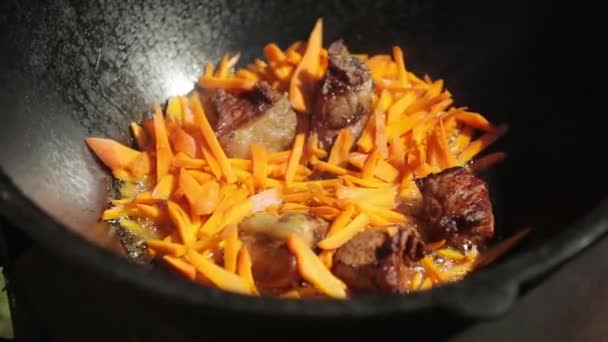 Las zanahorias y la carne se fríen en aceite en un caldero — Vídeos de Stock