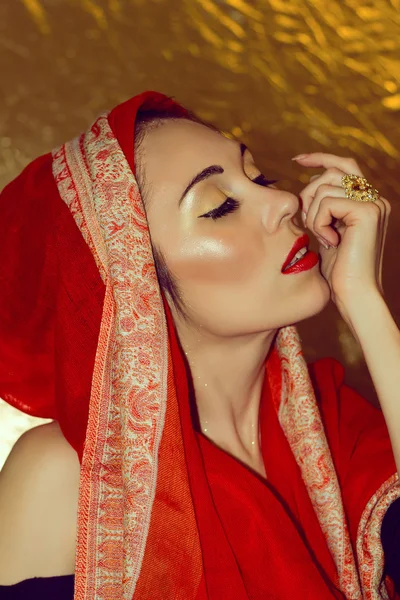 Une jeune femme arabe. Maquillage doré. Vêtements rouges . — Photo