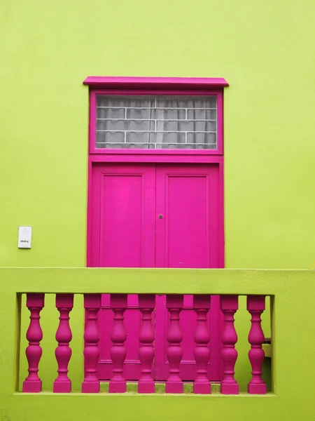 Un mur. Porte à balcon. Des couleurs vives. Rose foncé et jaune-vert — Photo