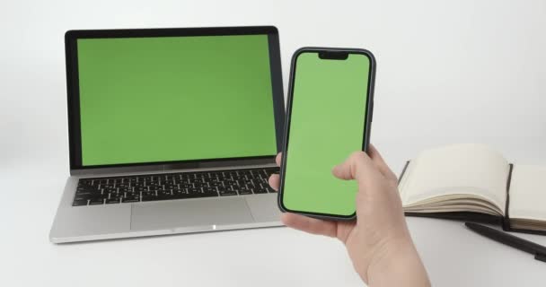 クロマキーモックアップスマートフォンやノートパソコンで 緑の画面で携帯電話を使用して女性の手 — ストック動画