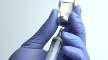 Doktor 'un Mavi Eldivenli Elleri Şırıngayı Cam Şişesinden Sıvı İlaçla Doldurun