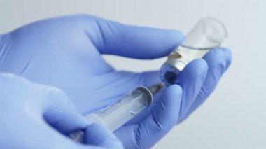 Close-up of Doctor's Hands in Blue Medical Gloves Filling Syringe with Liquid Medication from Glass Vial