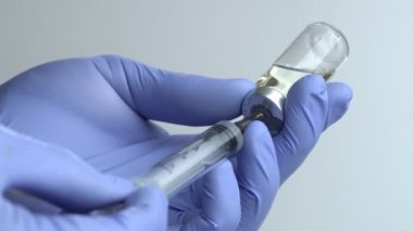 Close-up of Doctor's Hands in Blue Medical Gloves Filling Syringe with Liquid Medication from Glass Vial