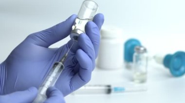 Close-up of Doctor's Hands in Blue Medical Gloves Filling Syringe with Liquid Medication from Glass Vial