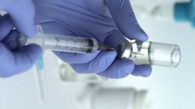 Close-up of Doctor's Hands in Blue Medical Gloves Filling Syringe with Liquid Medication from Glass Vial. Vertical video, 4k