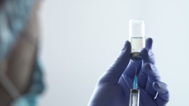 Eldiven takan doktor ya da hemşire şırıngayı cam şişeden çıkan sıvıyla dolduruyor. 4k