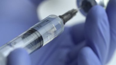 Şırınganın şişedeki sıvı ilaçlarla doldurulduğu yakın plan.