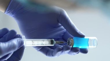 Eldiven takan doktor ya da hemşire şırıngayı cam şişeden çıkan sıvıyla dolduruyor. Dikey video, 4k 