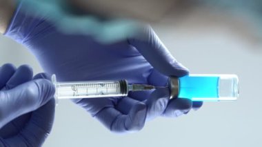 Eldiven takan doktor ya da hemşire şırıngayı cam şişeden çıkan sıvıyla dolduruyor. Dikey video, 4k 