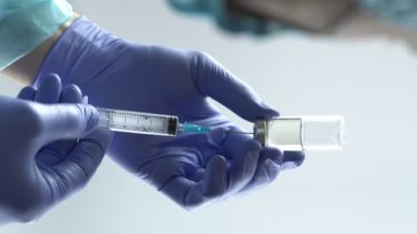 Eldiven takan doktor şırıngayı cam şişeden aşı ile dolduruyor. Dikey video, 4k